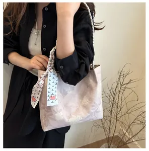 Détail d'un sac cabas floral avec poignées tressées et foulard en soie décoratif