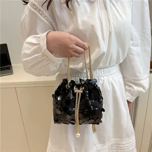Mini borsa a secchiello con paillettes nere, catena dorata e perle su un modello