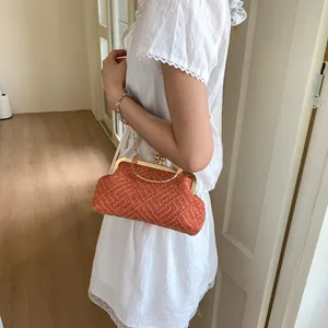 Close-up of orange woven floral handbag with gold metal ring handle and ball clasp