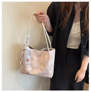 Détail d'un cabas rose à fleurs avec poignées tressées et accessoire foulard en soie décoratif