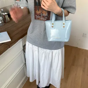 Detail of light blue mini bucket bag with glossy finish and gold rivet accents