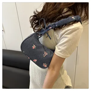 Side view of blue denim shoulder bag featuring pink rose and bow embroidery details