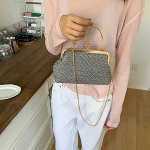 Detail of tweed crossbody bag with gold chain and vintage metal clasp closure