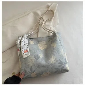 Détail du sac cabas en toile fleurie bleu clair avec anses en corde et foulard en soie