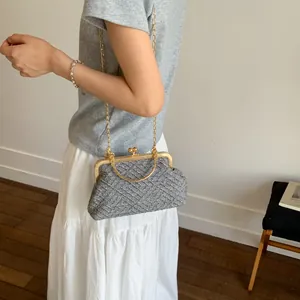 Detailed view of grey tweed cross-body bag with gold metal handle and chain strap