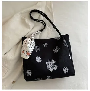 Gros plan détaillé d'un sac cabas noir avec motif floral blanc et détail foulard soie