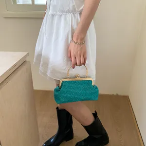 Detail of teal woven fabric handbag featuring gold ring handles and retro metal clasp
