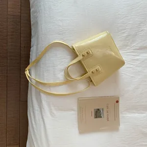 Top-down view of a cream yellow bucket bag with gold studs on a chic cafe-style background