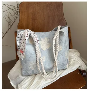 Détail d'un sac cabas floral bleu clair avec poignée en corde tressée et foulard en soie