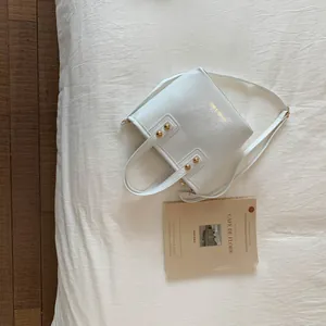 Detailed view of white bucket bag with gold studs and Fashion & Bags gold lettering