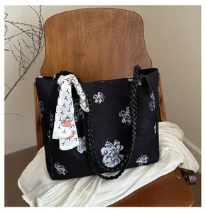 Détail du sac cabas noir avec motif floral blanc et foulard en soie décoratif sur chaise