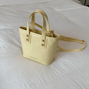 Close-up of light yellow fashion tote bag with gold studs and FASHION & BAGS logo