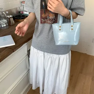 Elegant light blue bucket bag with glossy finish and gold rivets for casual wear