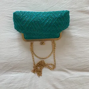 Macro detail of emerald green tweed fabric with vintage gold frame and clasp on a clutch