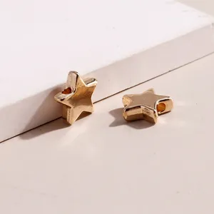 Detail of two star-shaped gold alloy pendants with side holes for DIY jewelry making