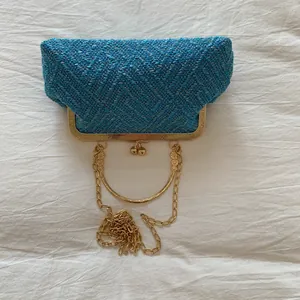 Close-up of blue woven tweed handbag with gold metal clasp and chain strap detail