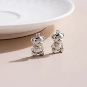 Detailed view of silver teddy bear charms with textured stitching and bow accents