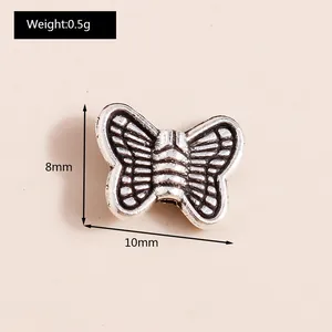 Macro detail of a 10x8mm vintage silver alloy butterfly pendant with engraved wing texture