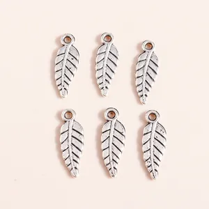 Detail view of vintage silver alloy feather pendants with intricate leaf vein textures