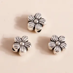Detailed macro view of vintage silver flower charms with intricate petal texture for DIY jewelry