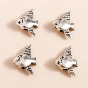 Close-up of retro silver alloy fish charms for DIY jewelry making showing fine fin textures