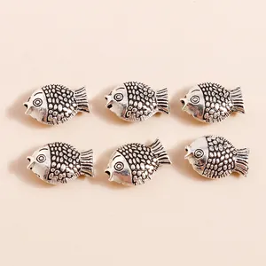 Macro detail of six antique silver fish alloy pendants with embossed scale textures