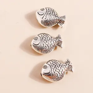 Macro detail of vintage silver carp charms featuring intricate scales and DIY metal texture