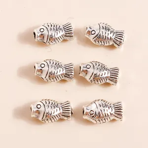 Detail of vintage silver fish pendants with intricate scale texture for DIY jewelry