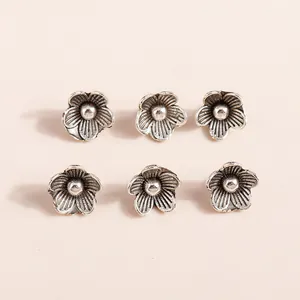 Macro shot of 6 antique silver flower pendants with five-petal texture for DIY jewelry