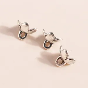 Three silver-plated floral alloy pendants for DIY jewelry making on beige background