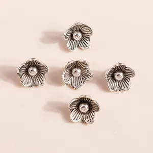 Five vintage silver floral alloy charms with petal textures and centerpiece detail