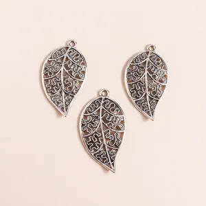 Detailed close-up of three vintage silver alloy hollow leaf charms for DIY jewelry making