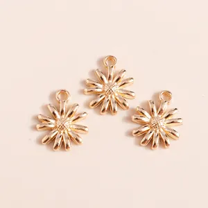Three gold daisy flower alloy pendants for DIY jewelry making on cream background