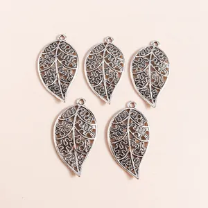 Five vintage silver hollow leaf charms with intricate floral patterns for DIY jewelry