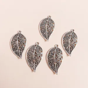 Five vintage silver hollow leaf pendants with intricate floral patterns for DIY jewelry