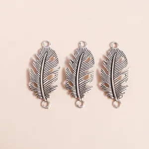 Macro detail of antique silver alloy feather charms with intricate carved textures