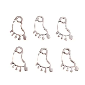 Macro detail of six silver-plated hollow footprint alloy charms for DIY jewelry