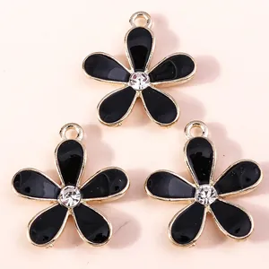 Macro detail of three gold-plated cherry blossom charms with black enamel and rhinestones