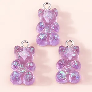 Close-up of three purple resin gummy bear charms with colorful glitter and silver loops