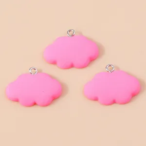 Dettaglio di tre ciondoli a nuvola in resina rosa opaca con anelli metallici per DIY