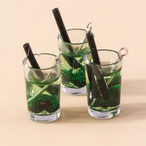 Dettaglio macro di mini ciondoli per bevande in resina verde con glitter e ganci