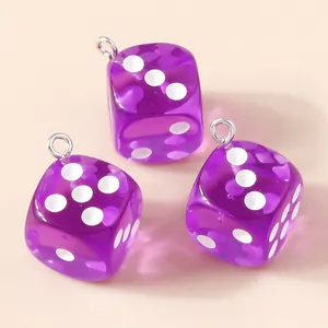 Détail macro de pendentifs dés en résine violette translucide avec anneaux argentés sur beige