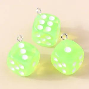 Vue détaillée de trois breloques dés en acrylique vert translucide avec anneaux argent