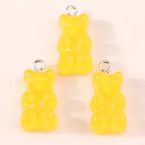Detailed view of three yellow resin gummy bear charms with silver metal rings for DIY jewelry