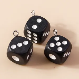 Détail de trois breloques dés en résine noire mate avec anneaux argentés pour bijoux DIY
