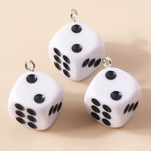 Gros plan de pendentifs dés en résine blanche avec points noirs et crochets