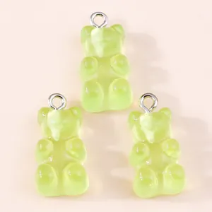 Close-up of translucent light green resin gummy bear charms with silver metal rings