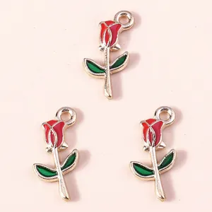 Three red enamel rose charms with gold alloy base and green leaves on pink background