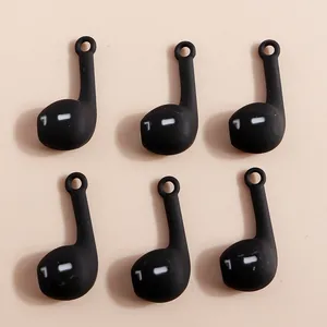 Detail of matte black headphone-shaped pendants with white L mark for DIY jewelry
