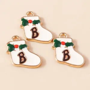 Close-up of white enamel Christmas sock pendants with green holly and letter B design